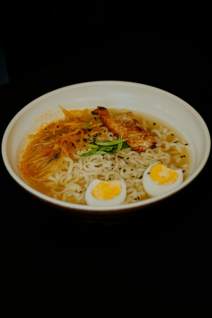 Delicious ramen bowl with boiled eggs, chicken, vegetables, and flavorful broth.