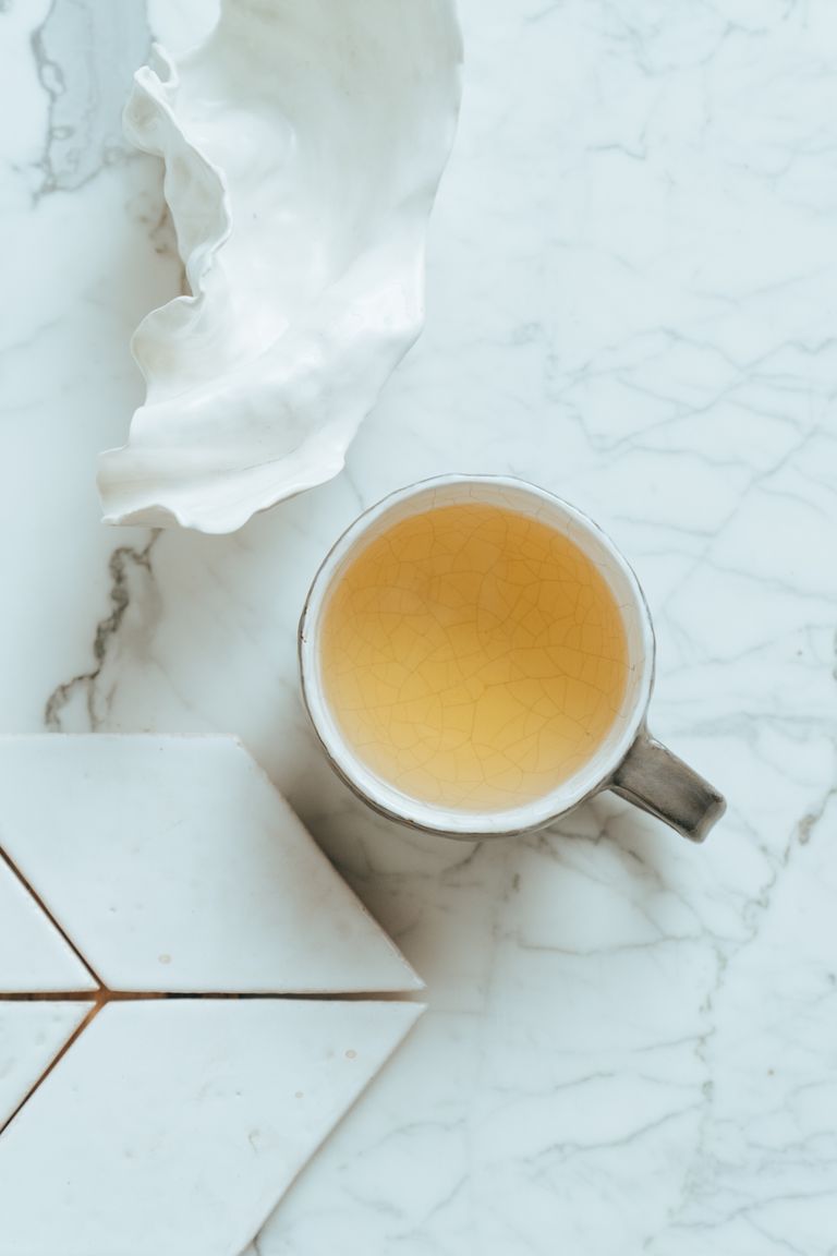 Artistic flatlay featuring a ceramic mug on a marble surface.